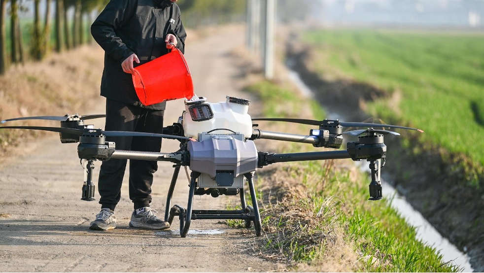 n operator prepares an agricultural drone for a pesticide run. The decision of when, where, and how much to spray is where AI is now replacing reactive guesswork.